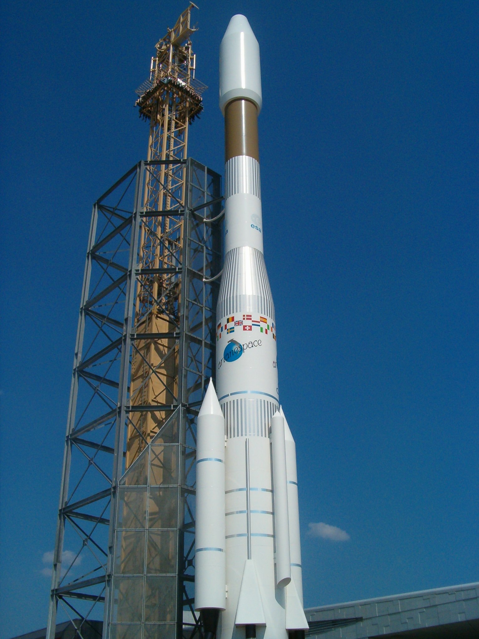 A full-scale Ariane 44LP rocket replica standing upright indoors, with strap-on boosters at its base