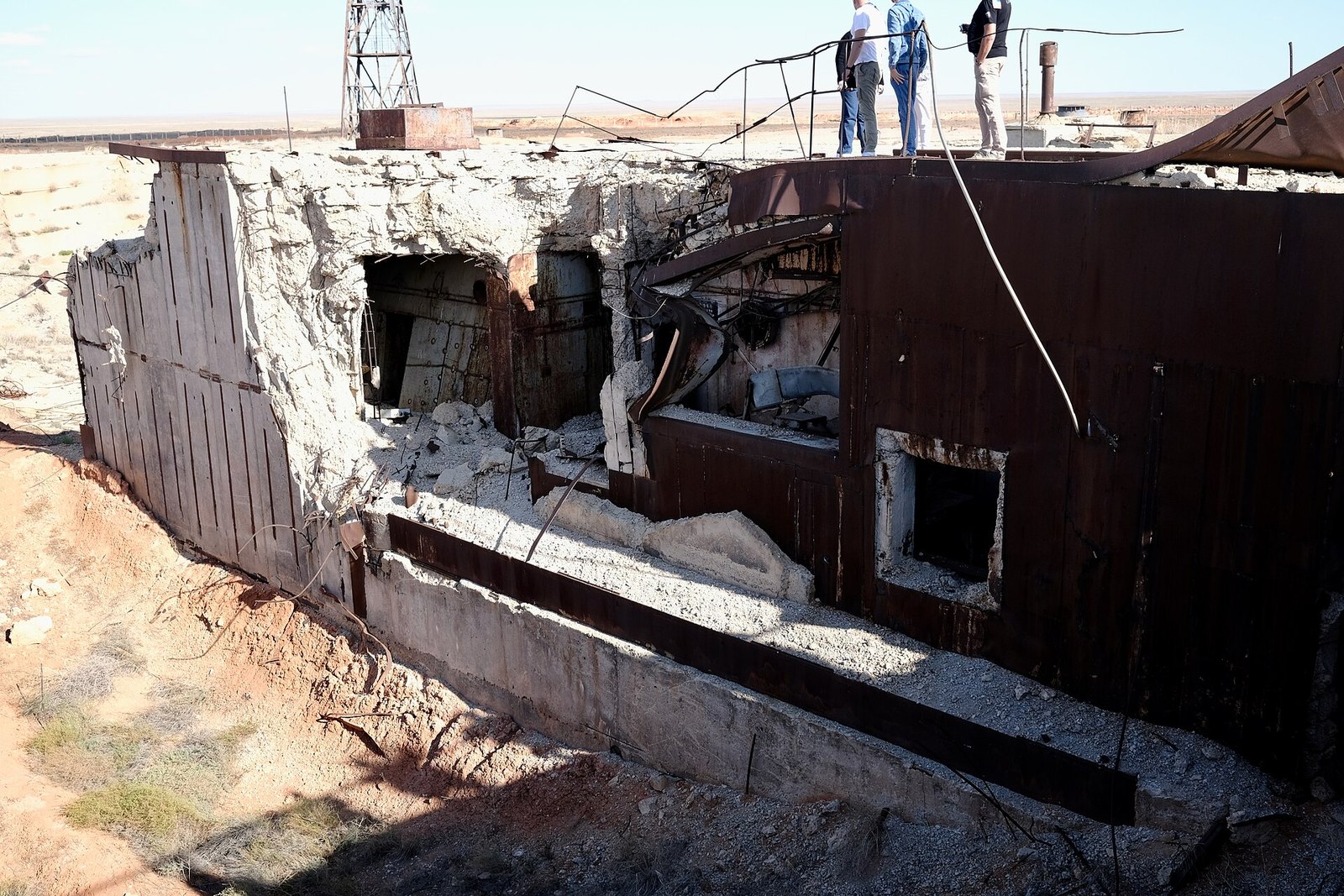 A disused concrete launch pad with twisted metal structures and overgrown ground, built for Zenit rockets at Baikonur
