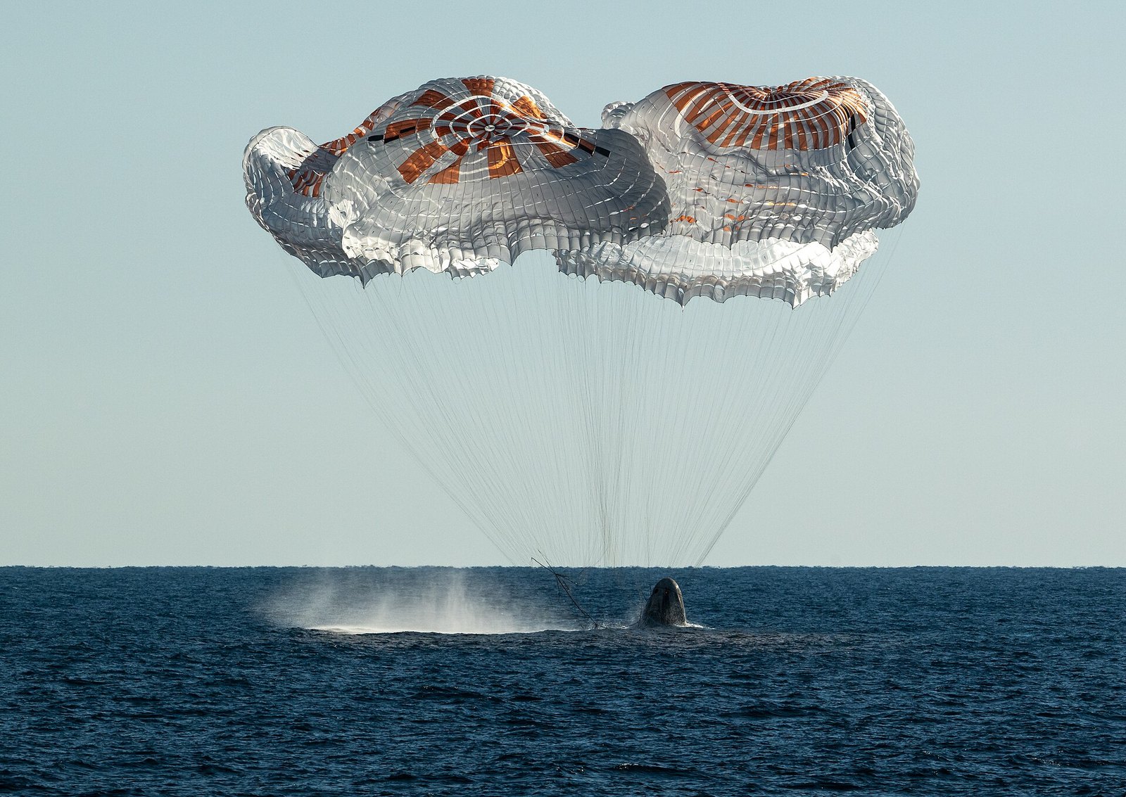 The Crew Dragon Freedom capsule floating in the sea after landing, with recovery boats nearby