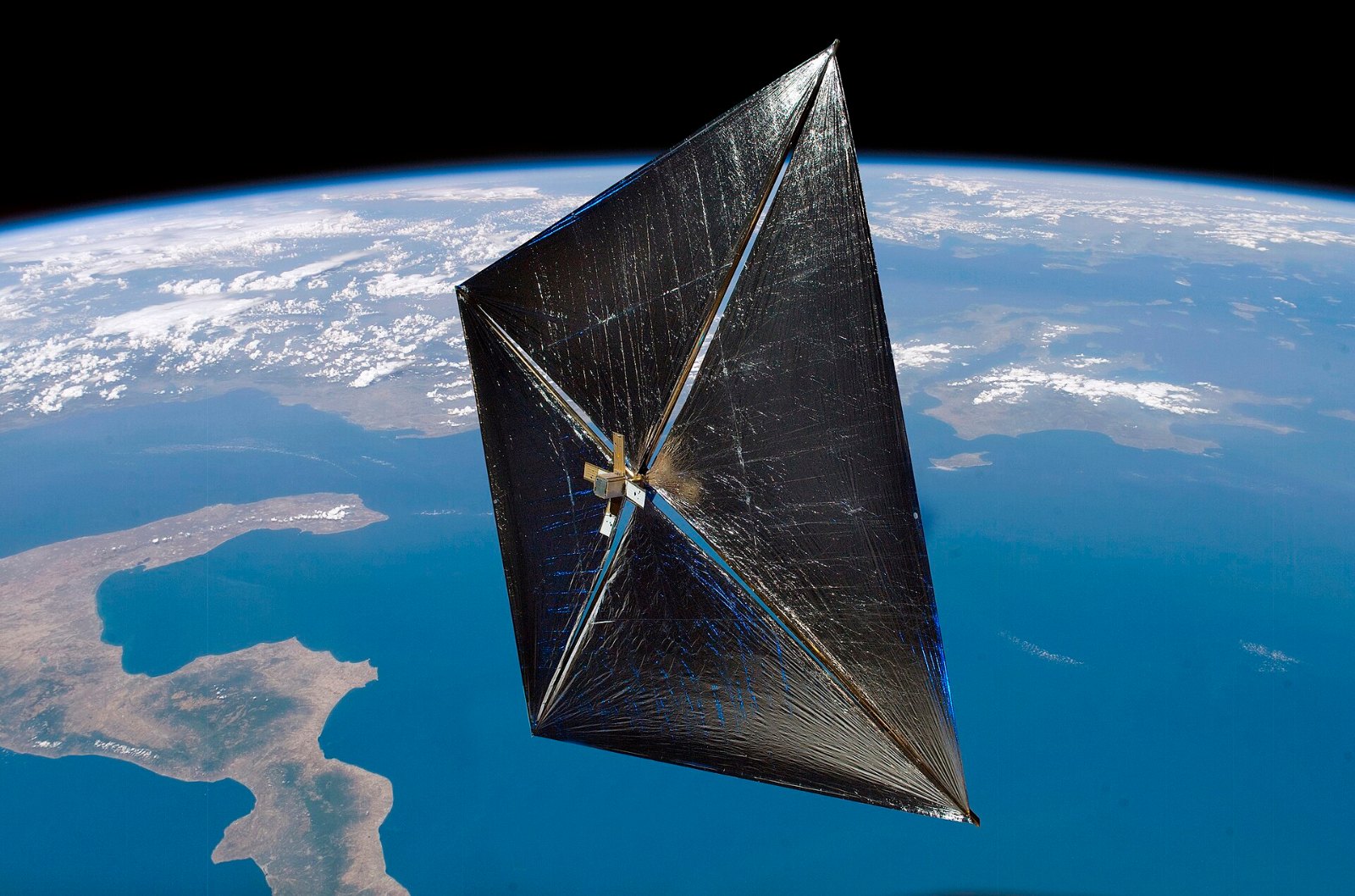 Illustration of the NanoSail-D CubeSat with its square sail deployed above Earth