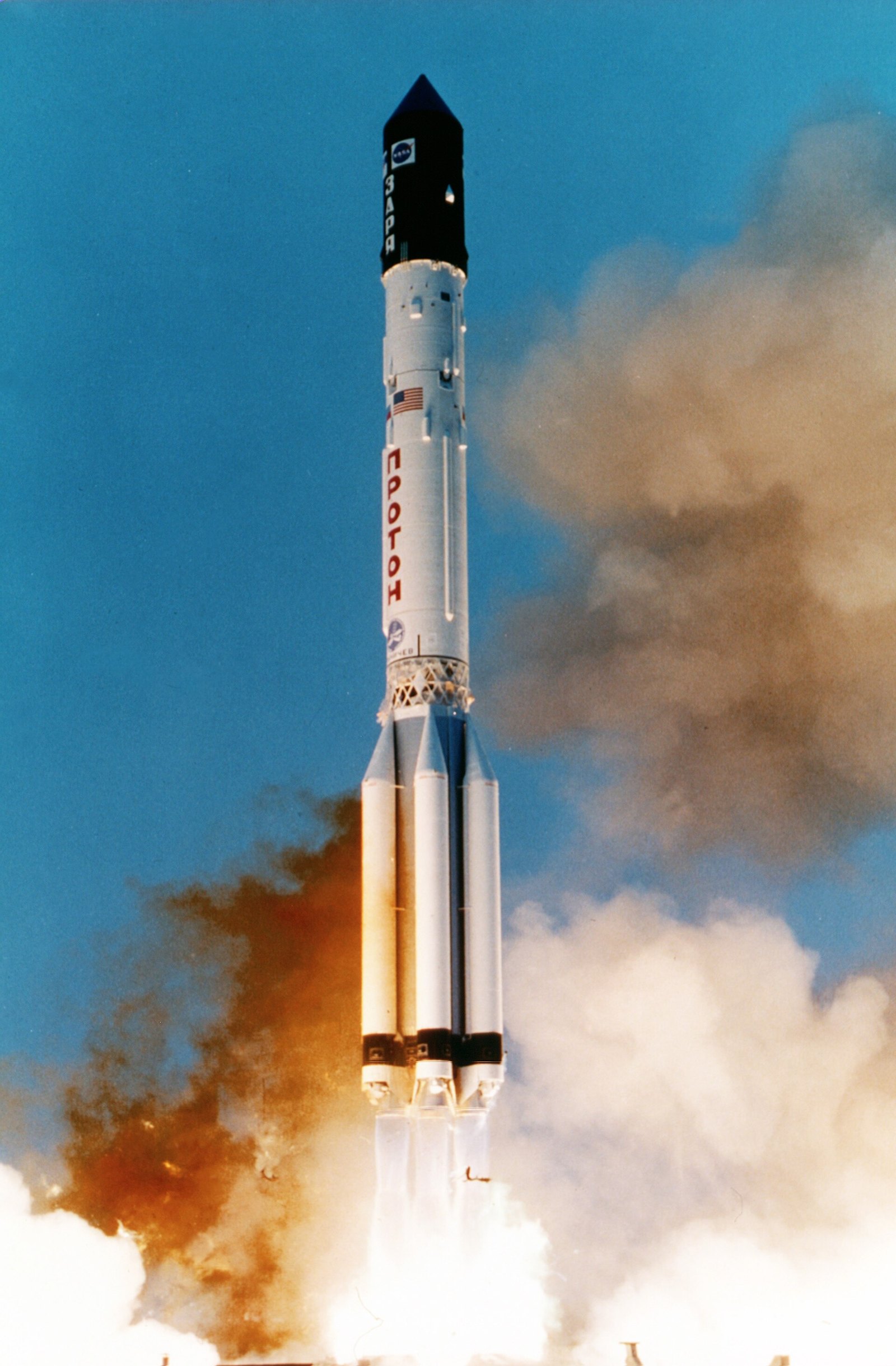 A Proton-K rocket climbing away from its launch pad trailing a bright exhaust plume