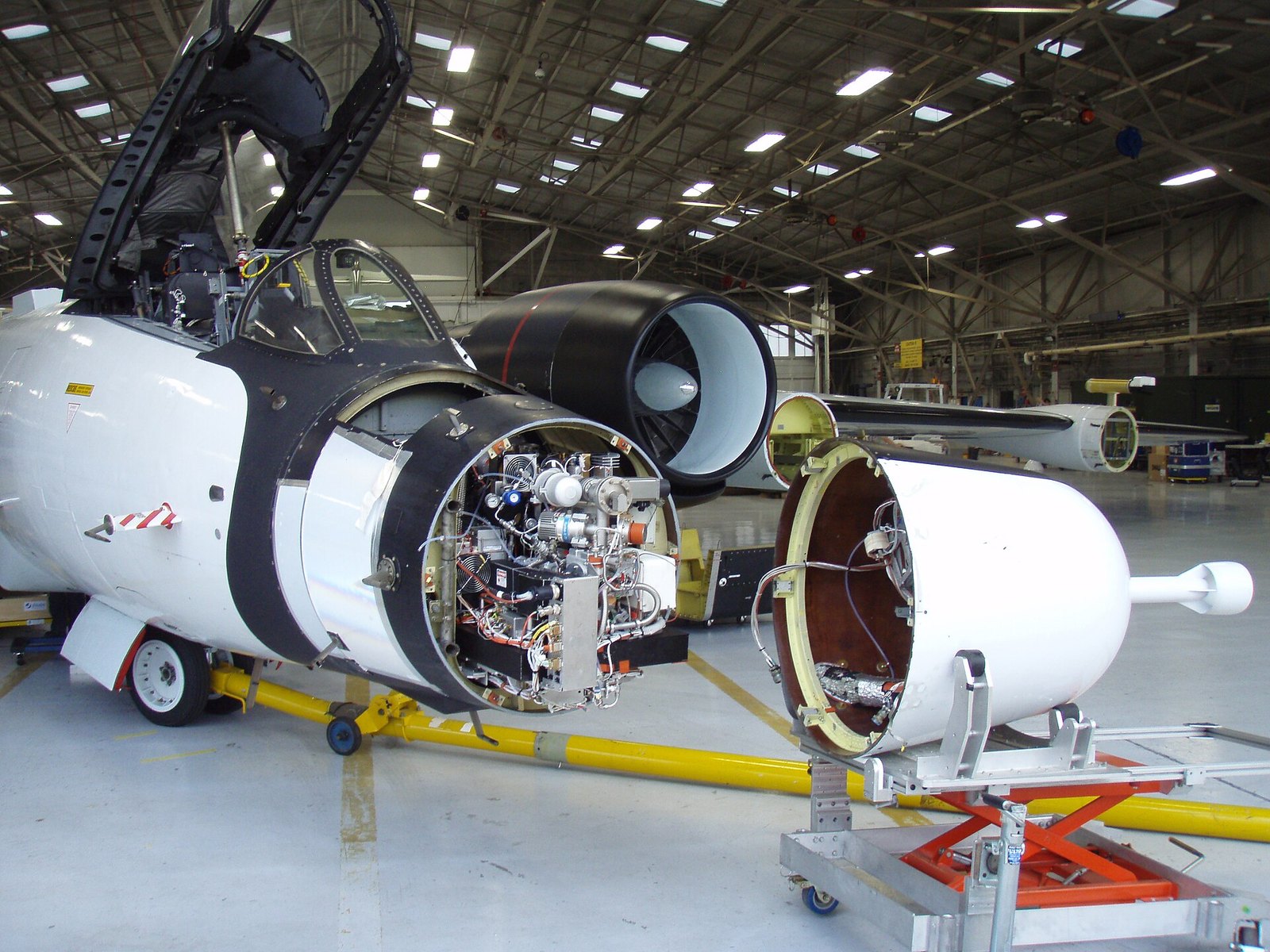 A cylindrical scientific instrument bolted into an equipment bay of a research aircraft